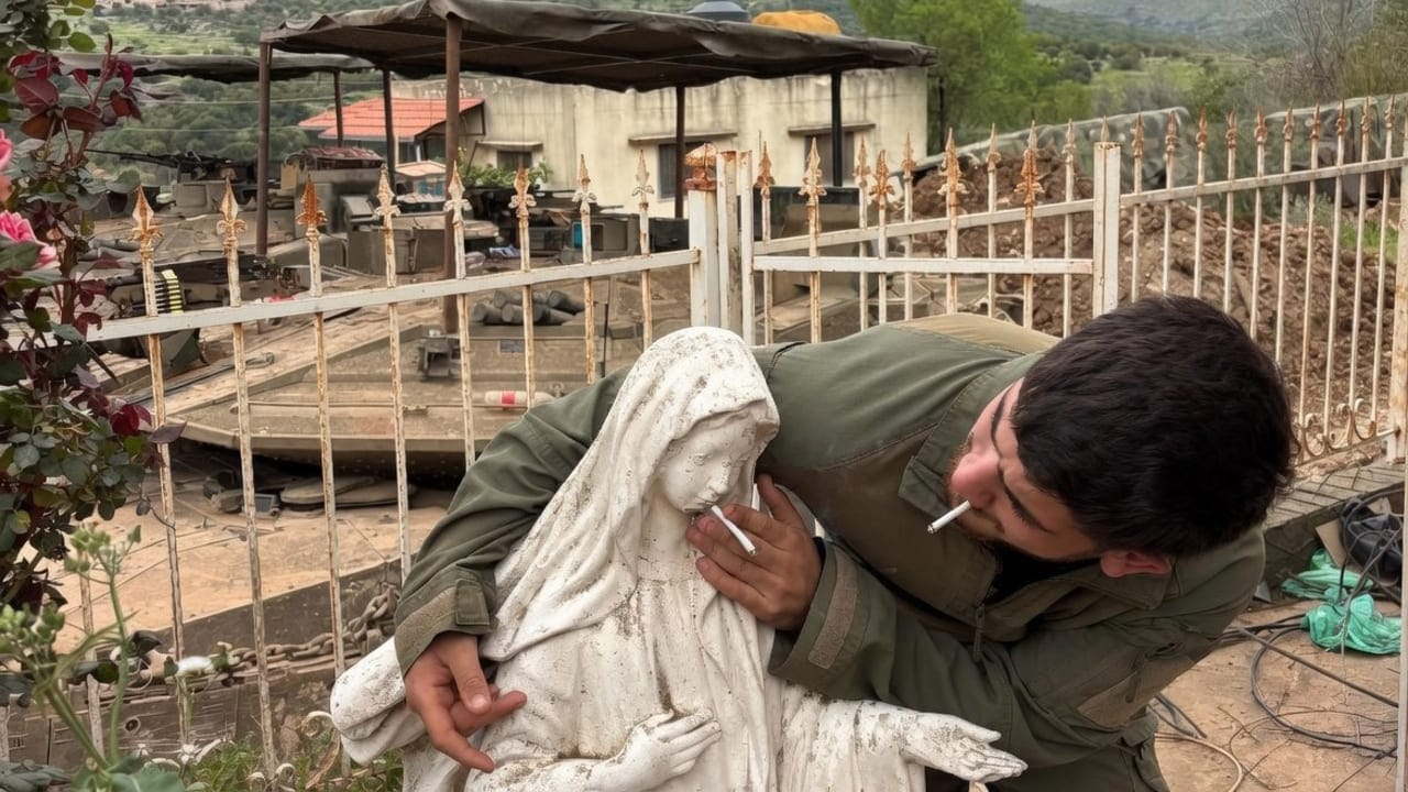 IDF soldier smoking cigarette with statue of Virgin Mary